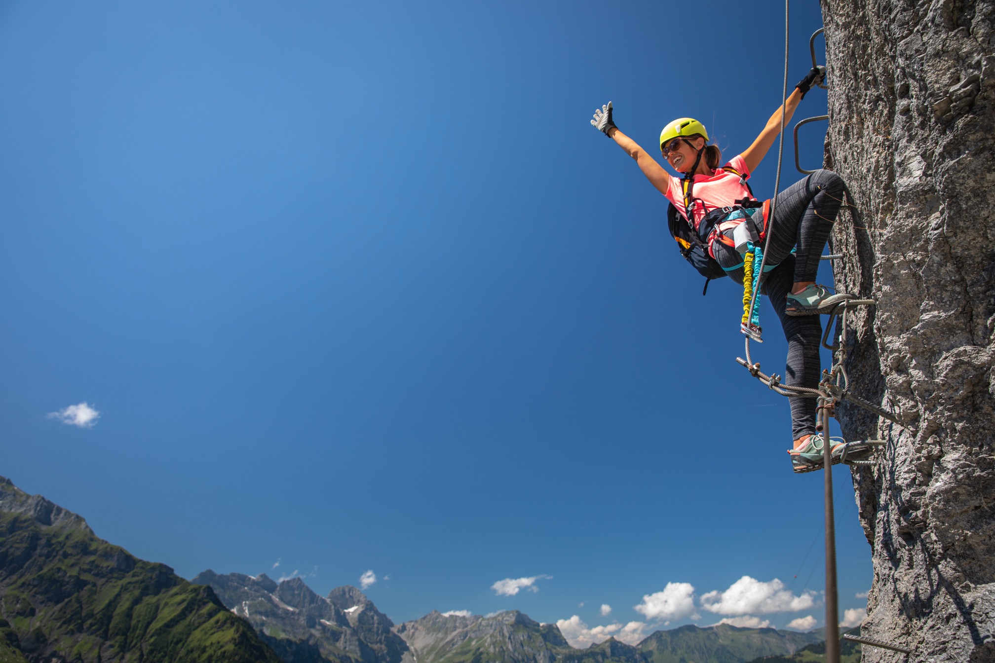 Pretty, female climber on a via ferrata – climbing on a rock in Swiss Alps